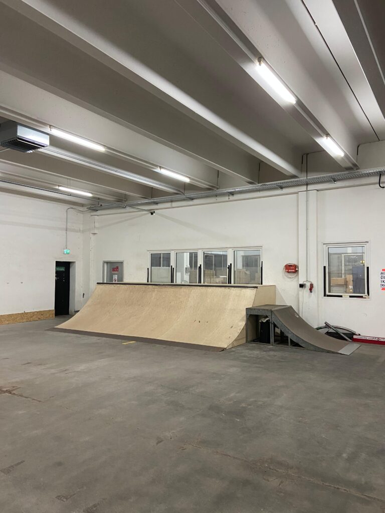 Das Bild zeigt eine sehr breite und mittelhohe Quarterpipe. Daneben steht noch eine kleine mobile Mini-Ramp.